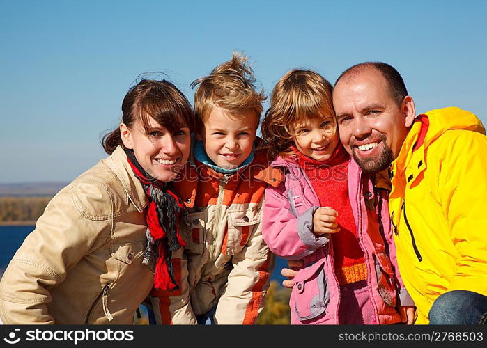 Family of four sunny autumn day. Everyone looks into camera.