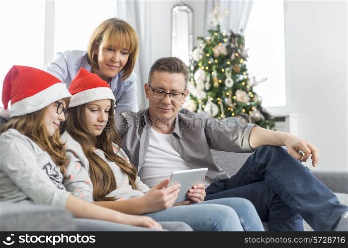 Family of four using digital tablet at home during Christmas