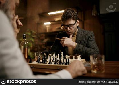 Family of intelligent people playing chess, smoking cigars and drinking whiskey. Senior and younger men sitting at table looking at chessboard. Smart games. Family of intelligent people playing chess, smoking cigars and drinking whiskey