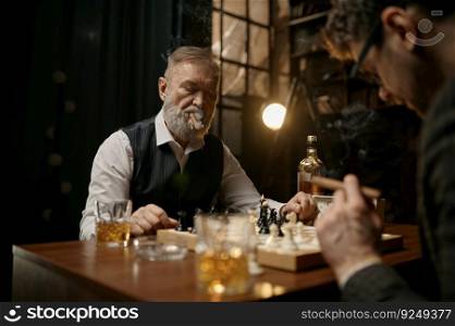 Family of intelligent people playing chess, smoking cigars and drinking whiskey. Senior and younger men sitting at table looking at chessboard. Weekend evening. Family of intelligent people playing chess, smoking cigars and drinking whiskey