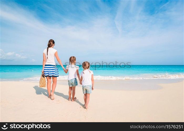 Family of mother and children on the beach. Adorable little girls and young mother on tropical white beach