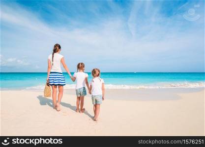 Family of mother and children on the beach. Adorable little girls and young mother on tropical white beach