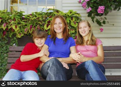 Family of mother and children sitting in front of their house
