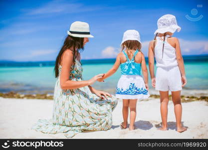 Family of mother and kids on the beach vacation. Adorable little girls and young mother on tropical white beach