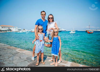 Family of parents and kids on european vacation on Mykonos Island. Parents and kids at street of typical greek traditional village on Mykonos Island, in Greece