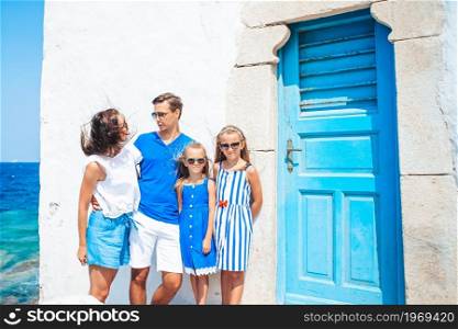 Family of parents and kids on european vacation on Mykonos Island. Parents and kids at street of typical greek traditional village on Mykonos Island, in Greece