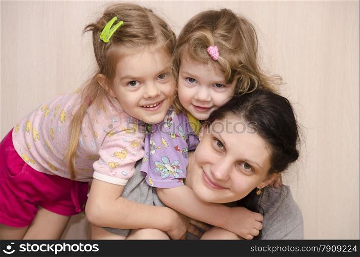 family of the house, my mother, two-year and four-year-old daughter. The younger daughter hung on the mother&#39;s neck, the eldest daughter lay down on the shoulder of the younger. Smile and look in the frame.