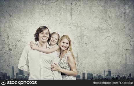 Family of three. Happy family of mother father and daughter against cement wall