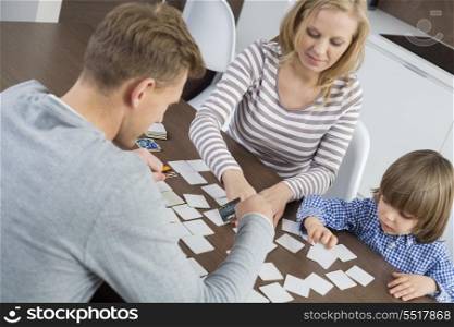 Family of three playing cards at home