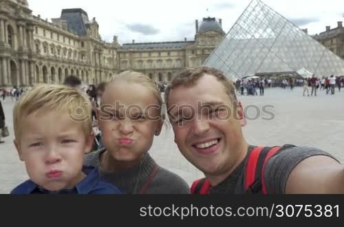 Family of three shooting selfie video near the The Louvre museum in Paris. Mother, father and son laughing and making funny faces