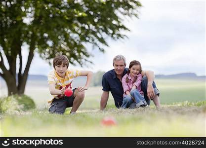 family of three sitting on the grass