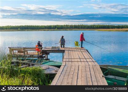 family on a fishing trip on a pier in the background of a picturesque lake