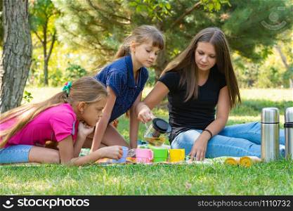 Family on a picnic, girl pours tea in glasses