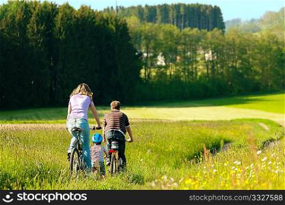 Family on a trip with their bicycles in a wonderful scenery, since their son is so young he is riding a training bike