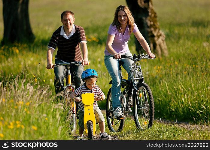 Family on a trip with their bicycles in a wonderful scenery, since their son is so young he is riding a training bike