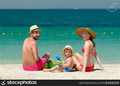 Family on beach. Two year old toddler boy playing with beach toys with mother and father on beach.