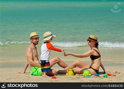 Family on beach. Two year old toddler boy playing with beach toys with mother and father on beach.