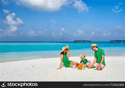 Family on beach, young couple in green with three year old boy. Summer vacation at Maldives.