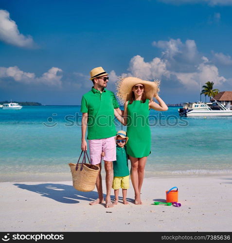 Family on beach, young couple in green with three year old boy. Summer vacation at Maldives.