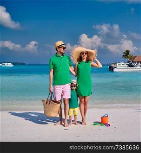 Family on beach, young couple in green with three year old boy. Summer vacation at Maldives.