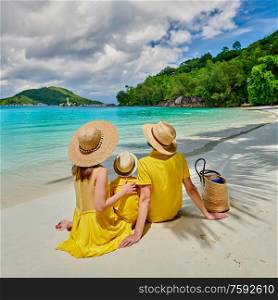Family on beach, young couple in yellow with three year old boy. Summer vacation at Seychelles. Port Launay, Mahe.
