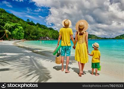 Family on beach, young couple in yellow with three year old boy. Summer vacation at Seychelles. Port Launay, Mahe.