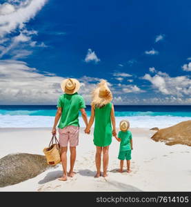 Family on beautiful Anse Intendance beach, young couple in green with three year old toddler boy. Summer vacation at Seychelles, Mahe.