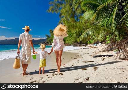 Family on beautiful Anse Soleil beach, young couple in white with three year old toddler boy. Summer vacation at Seychelles, Mahe.