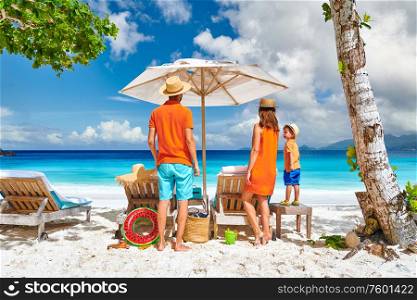 Family on beautiful Petite Anse beach, young couple with three year old toddler boy. Summer vacation at Seychelles, Mahe.