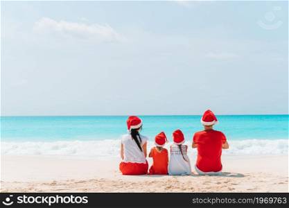 Family on Christmas holiday on the beach. Happy family with two kids in Santa Hat on summer vacation