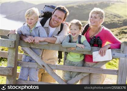 Family on cliffside path leaning on fence and smiling