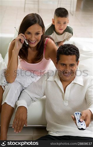 Family on Couch Using Cell Phone and Remote Control