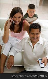 Family on Couch Using Cell Phone and Remote Control