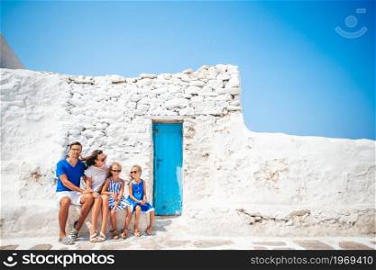 Family on european vacation on Mykonos Island. Parents and kids at street of typical greek traditional village on Mykonos Island, in Greece