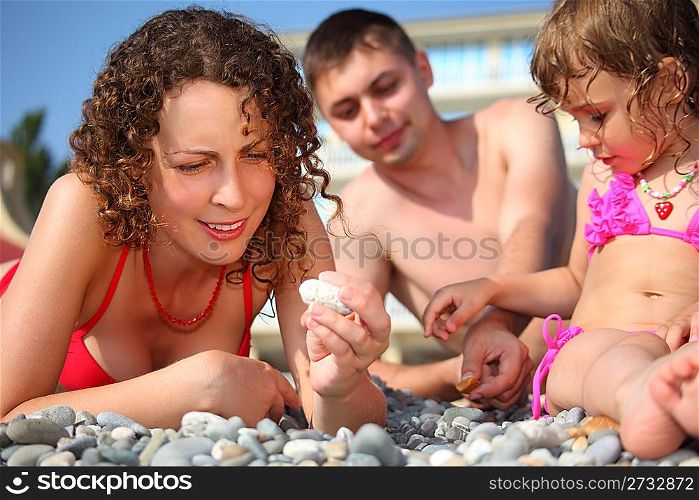 family on pebble in swimwear
