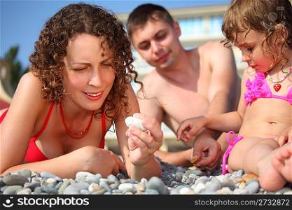 family on pebble in swimwear
