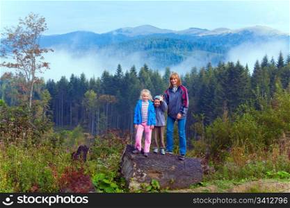 Family on september Carpathian mountain hill and cloudy morning view behind