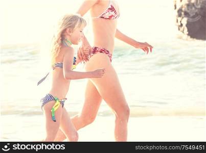 Family on the beach on sunset. Mother and daughter runing together.