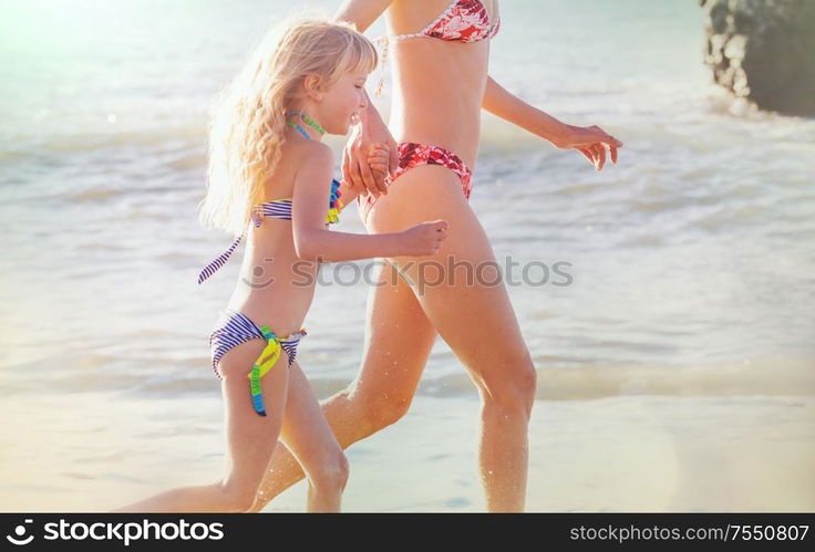 Family on the beach on sunset. Mother and daughter running together.