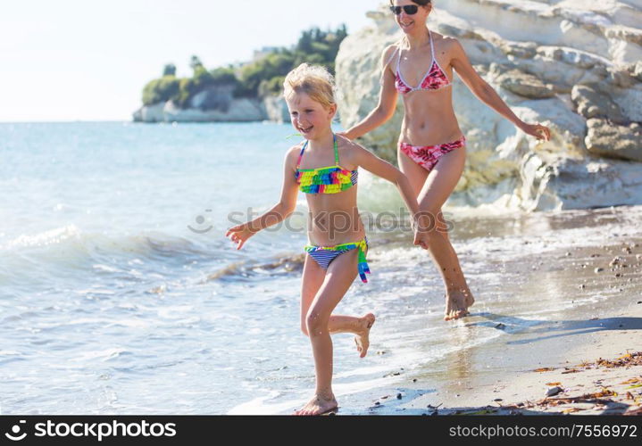 Family on the beach on sunset. Mother and daughter running together.