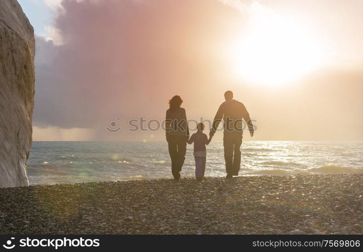 Family on the beach on sunset. Mother and daughter running together.