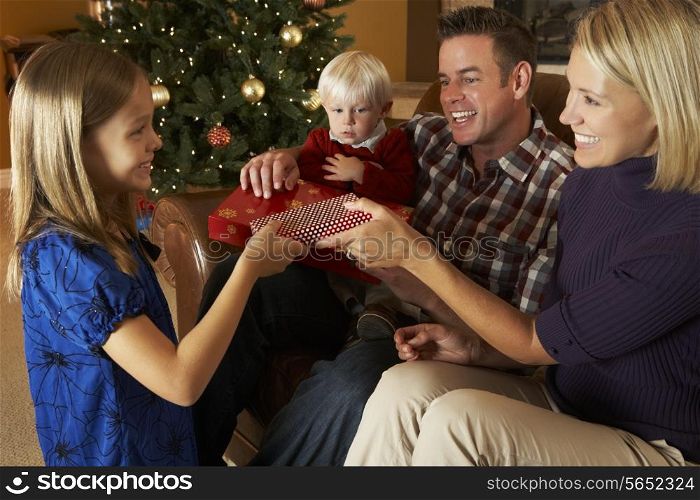 Family Opening Presents In Front Of Christmas Tree