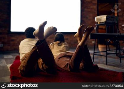 Family or friends enjoy rest together. Couple looking at blank projector screen view from back. Family couple looking at blank projector screen