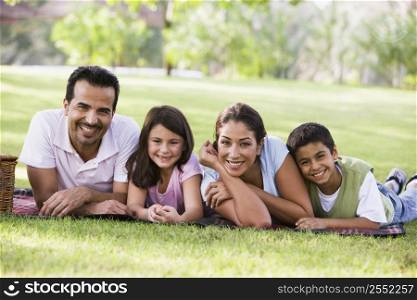 Family outdoors in park with picnic smiling (selective focus)