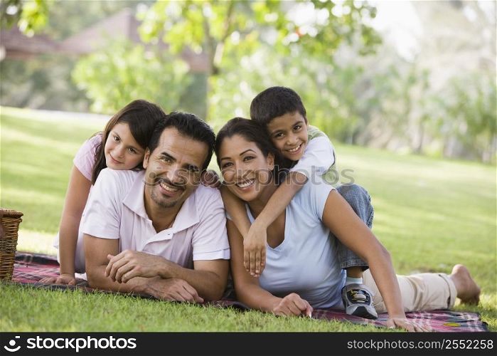 Family outdoors in park with picnic smiling (selective focus)