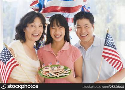 Family outdoors on fourth of July with flags and cookies smiling