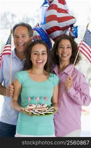 Family outdoors on fourth of July with flags and cookies smiling