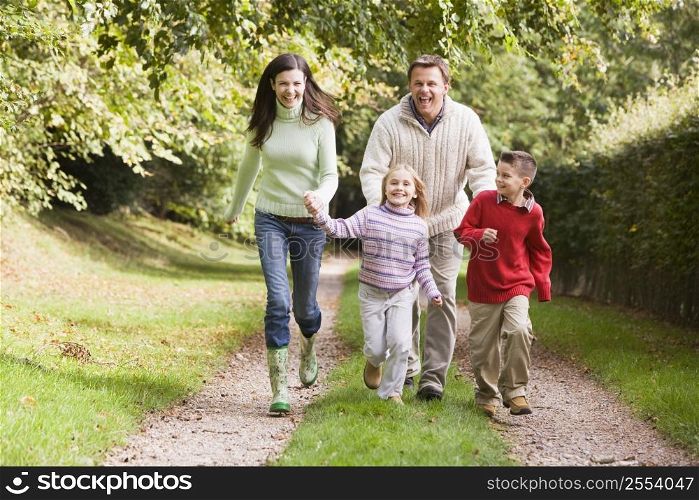 Family outdoors walking on path holding hands and smiling (selective focus)