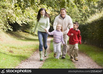 Family outdoors walking on path holding hands and smiling (selective focus)
