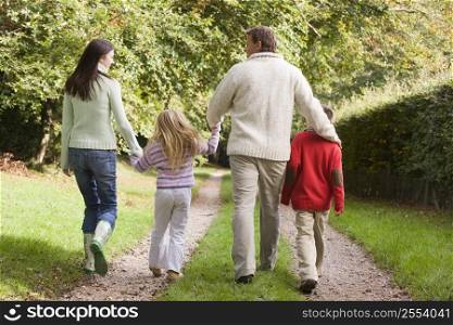 Family outdoors walking on path holding hands (selective focus)